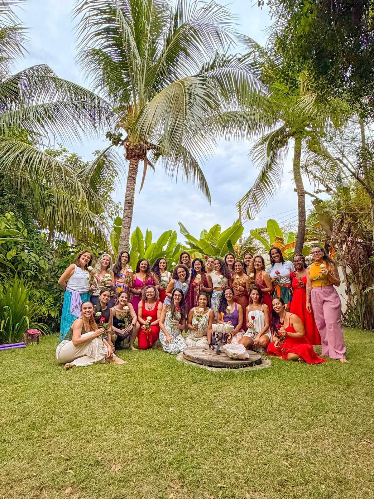 Grupo de mulheres reunidas com rosas em um encontro presencial ao ar livre